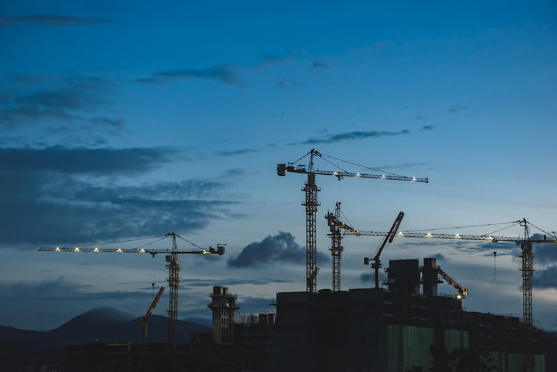 Baustelle mit mehreren Baukränen in der Abenddämmerung – Sinnbild für die angespannte Lage der deutschen Bauwirtschaft 2026.